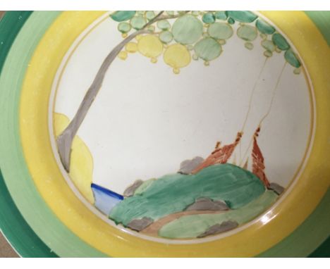 A Clarice Cliff plate decorated with house and trees .