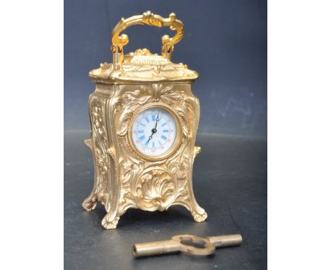 A late 20th century gilt metal French Rococo style miniature carriage clock. The clock have a swing handle and being highly d