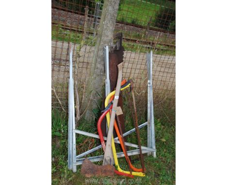 A quantity of saws, axe and a metal sawing horse.