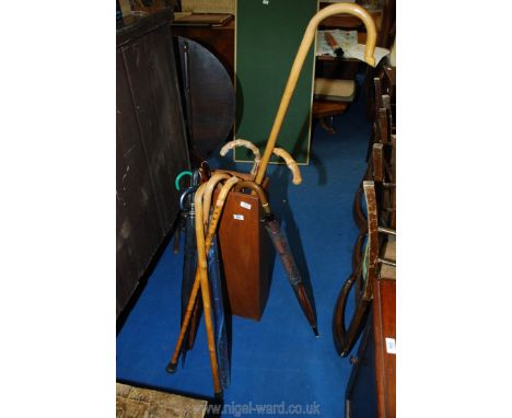 Wooden stick stand and quantity of walking sticks and umbrellas.