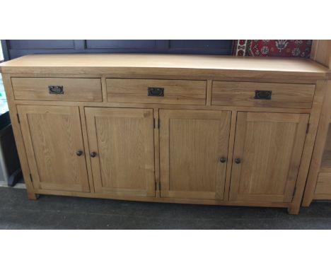 A solid light oak sideboard with three drawers and four cupboards.   H: 100cm  w: 200cm  d: 45cm 