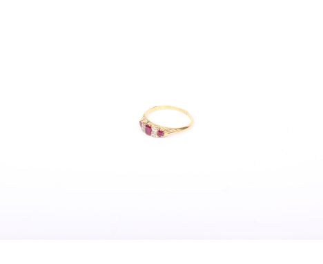 An 18k gold three stone ruby and diamond ring. central oval cut ruby flanked by 4 old cut diamonds with ruby accents. 2.9 g  