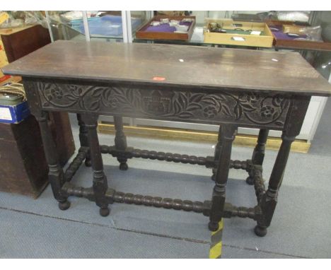 A late 17th/early 18th century oak side table having eight legs with bobbin turned supports and floral carved decoration, 75h