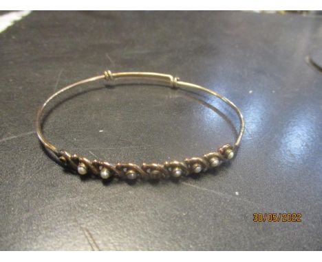 A 9ct gold bangle set with pearls within an interwoven setting, two pearls deficient, weight 3.2g 