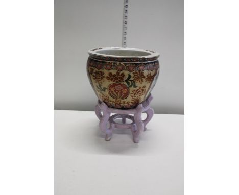 A Chinese ceramic fish bowl on a wooden stand 
