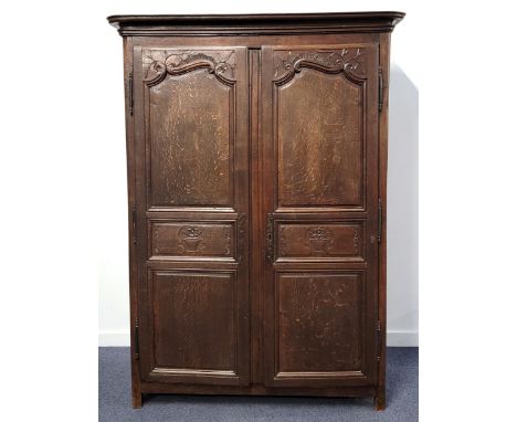 ANTIQUE RUSTIC OAK WARDROBEwith cornice to top, the doors with carved foliate and flower design with external iron finial hin