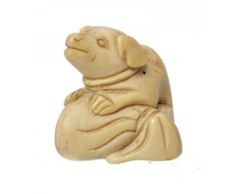 A JAPANESE IVORY NETSUKE IN THE FORM OF A PUPPY ON A SACK, MEIJI PERIOD  27mm h ++Some discolouration and dust, not cracked o