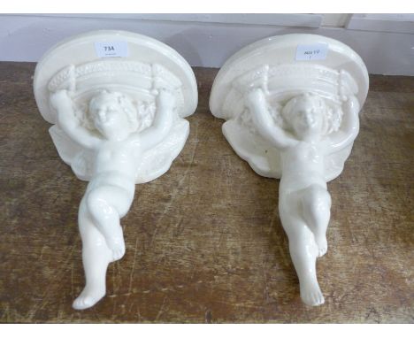 A pair of cherub wall brackets, marked 'Poole, England'