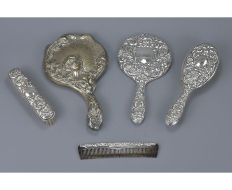 An English antique silver dressing set, to include a hand mirror, two brushes and a comb. Together with an art nouveau hand m