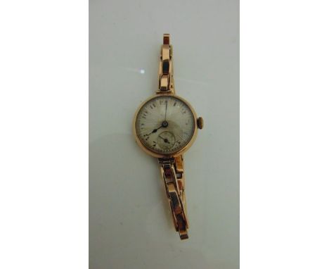 A vintage ladies wristwatch with 9ct gold case and strap with silver engine turned dial
