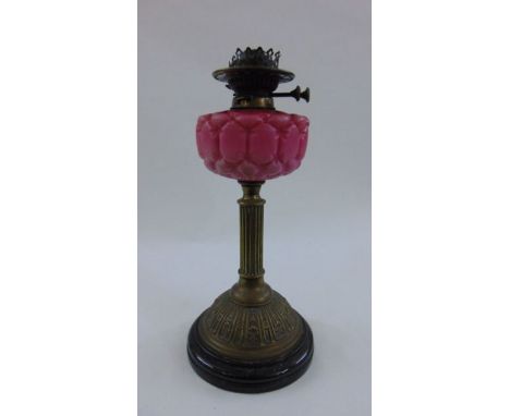 A Victorian embossed brass oil lamp with satin glass font in the form of a cushion with a Wright & Butler twin burner wick