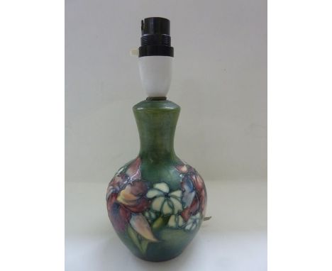 A Moorcroft vase shaped table lamp with trailing floral detail including iris upon a green ground with impressed Moorcroft ma