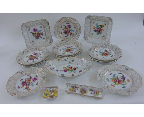 A collection of Dresden porcelains comprising twelve plates with hand painted floral detail within pierced lattice work borde