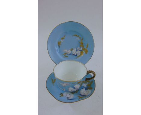 A Royal Worcester trio with painted and gilded fan tailed pigeons and foliage decoration on a pale blue ground, signed C John