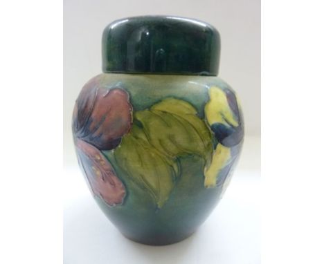 A Moorcroft oviform ginger jar and cover with trailing floral frieze upon a deep green ground with impressed Moorcroft mark, 