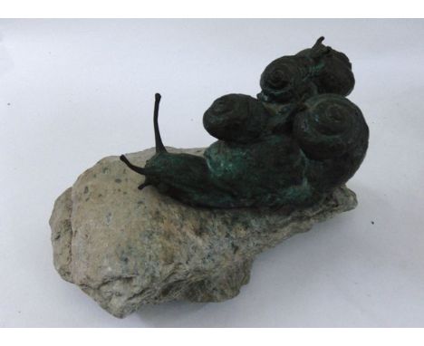 A bronze group of five snails on a natural rock base