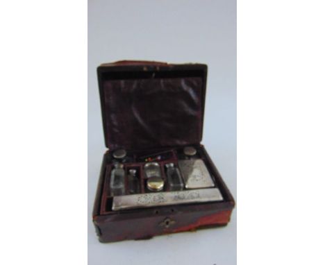 A Victorian maroon leather travelling box containing a collection of glass scent, toilet water and other bottles, all with si