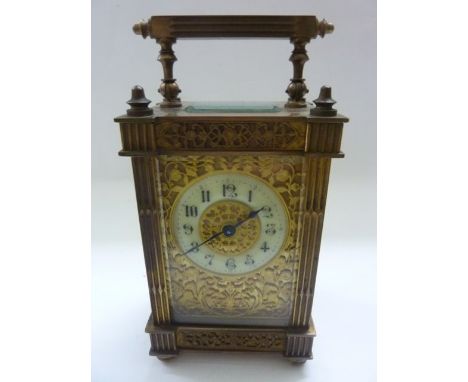 A late 19th century brass carriage clock, the case with reeded column supports and handle, the circular dial with fretted mas