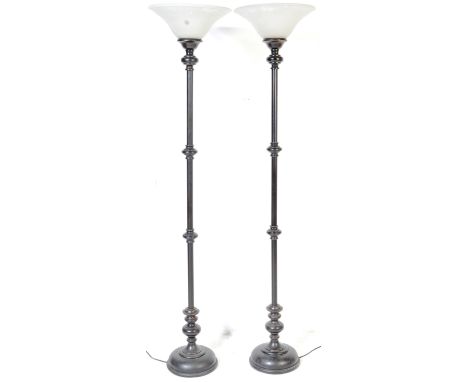A pair of contemporary metal upright floor standing light / lamps. The lamps having white glass shades with metal turned colu
