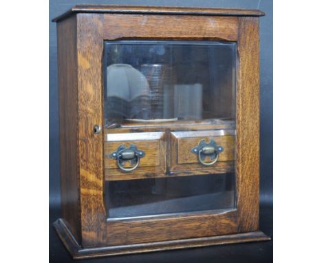 A 19th Century Victorian oak smoker's cabinet. The cabinet having a flared top, pipe holders inside with twin drawers, glazed