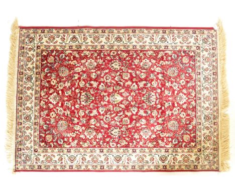 A vintage 20th century Persian Islamic carpet rug having a red background with foliate decoration and tassels to each side. 1