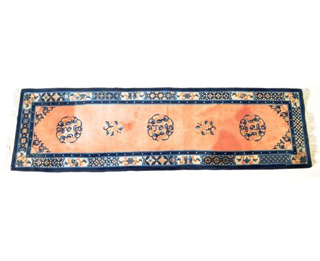 A vintage 20th century Chinese oriental rug / runner having foliate decoration set within a border with tassels to each end.&