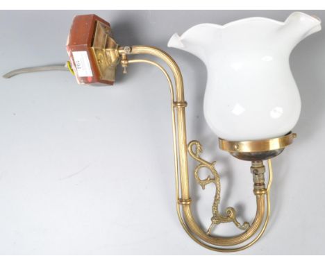 An early 20th Century brass wall sconce gas lamp light having a shaped glass floral shade with scrolled brass arm. Converted 