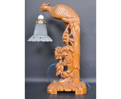 A vintage 20th century Chinese oriental table lamp having a finely detailed carved stand in the form of a peacock raised on a