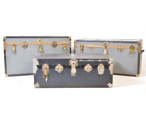 A collection of three vintage 20th century grey and gilt metal bound steamer trunks by Overpond + Mossman. The trunks having 