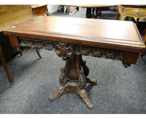 An antique mahogany fold-over card-table with baize lined interior having an elaborately carved and moulded base (some restor