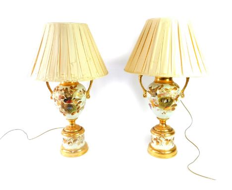 A pair of Staffordshire late 19thC pottery vases on stands, of twin handled baluster form, painted and gilded with nesting bi