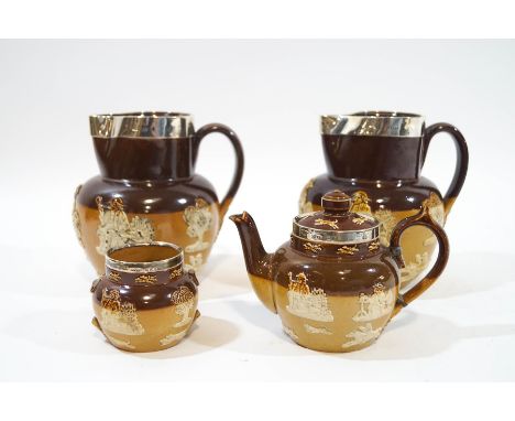 A pair of Royal Doulton saltglazed stoneware jugs, mounted with silver rims, 15cm high, together with a similar small teapot 