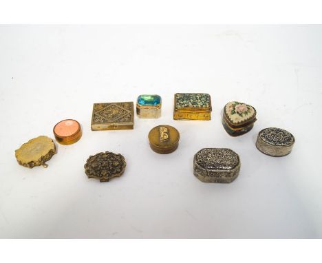 A collection of nine pill boxes, including a heart shaped tapestry example