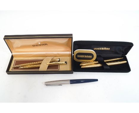 A Waterman fountain pen and ballpoint pen set, the fountain pen with 18K nib, in textured gold tone body, a Sheaffer gold pla