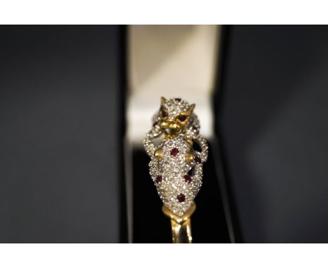 A diamond and ruby panthers bangle, stamped '9K', the confronting panthers to the frontispiece pave set with small brilliant 