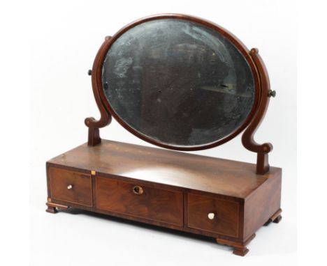 A Georgian mahogany dressing table swing mirror, the oval cushion framed mirror above three drawers, crossbanded, raised on o