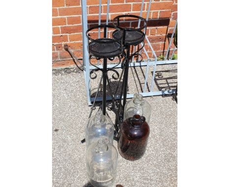 Four vintage cider glass jugs and a pair of metal pot stands