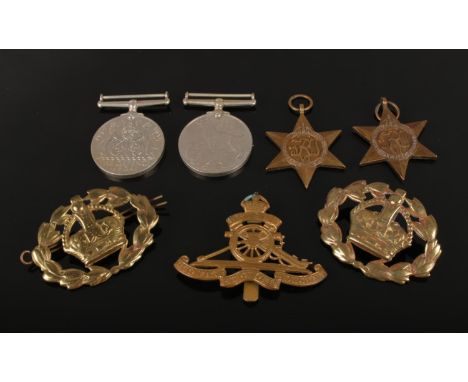 A group of four World War II medals, Royal Artillery cap badge and two British Army Warrant Officers sleeve badges. Medals in