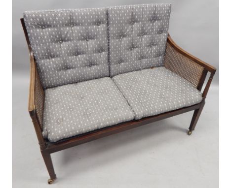 An early 20thC mahogany bergere sofa, in George III style, with loose patterned cushions, turned supports, on square tapering