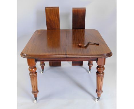 A Victorian mahogany extending dining table, the top with a moulded edge and two loose leaves, on turned and fluted legs with