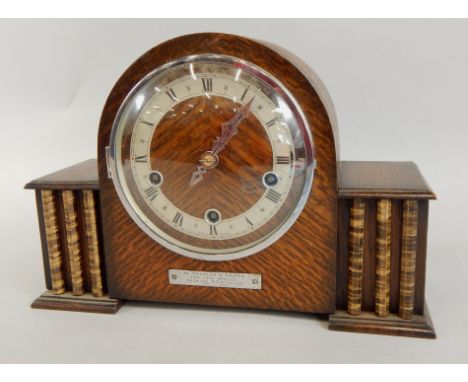 An Art Deco style mantel clock, the oak case with simulated columns, silvered chapter ring, Westminster chime and presentatio