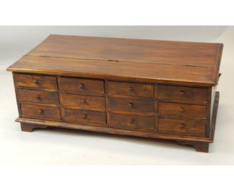 A modern hardwood coffee table, the top with a hinged lid, revealing a recess, and an arrangement of twelve drawers to the si