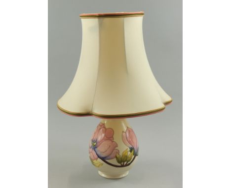 A Moorcroft lamp base, with tube lined decoration of pink flowers, on a cream ground with a shade, 43cm high overall