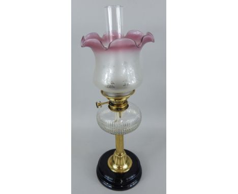 A Victorian oil lamp, with cut glass clear reservoir, brass and ebonised terracotta base, with later etched cranberry shade a