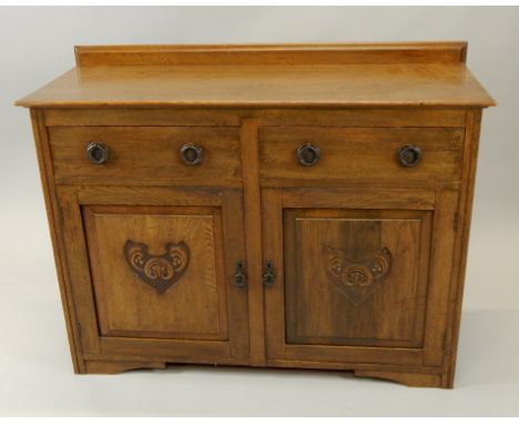 An early 20thC oak side cabinet, with a raised back, above two frieze drawers and two carved panel doors, on bracket feet, 12