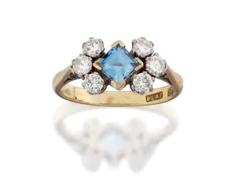 the square step cut aquamarine in a yellow claw setting, flanked by trios of round brilliant cut diamonds in white claw setti