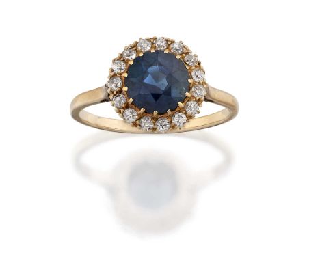 the round cut sapphire within a border of old cut diamonds, in yellow claw settings, to a yellow tapered shoulder plain polis