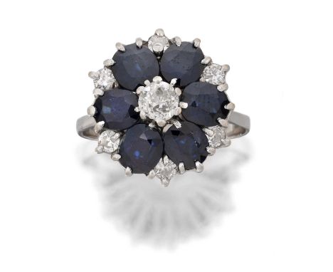 the old cut diamond within a border of oval cut sapphires and smaller round brilliant cut diamonds, in white claw settings, t