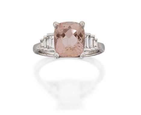 the cushion shaped pink topaz flanked by trios of stepped baguette cut diamonds, in claw settings, to a plain polished shank,
