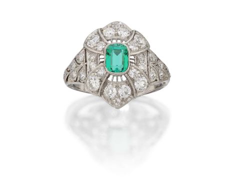 the emerald-cut emerald within a border of old cut diamonds spaced by a wirework frame, in white claw and millegrain settings